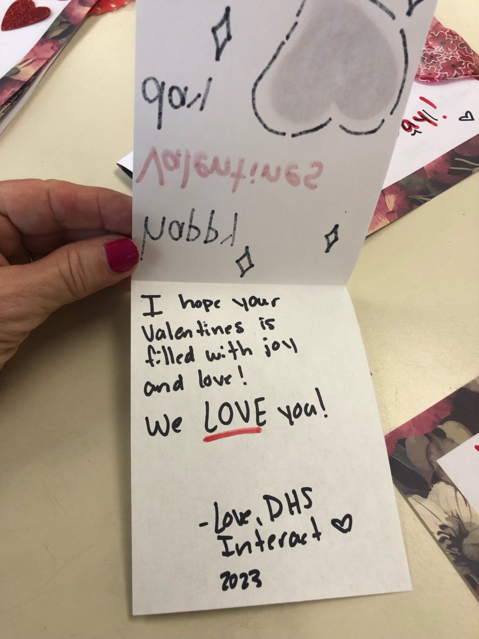 A hand holding a piece of paper with writing on itDescription automatically generated